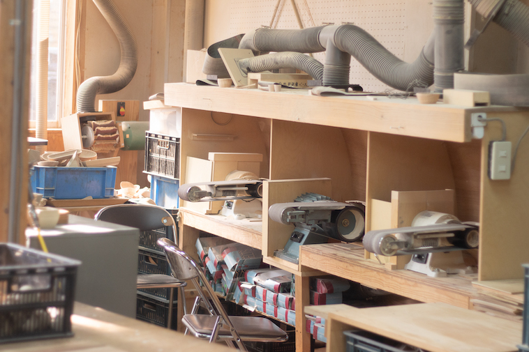 【写真】木製の机の上に器を彫るようの機械が並んで置いてある。