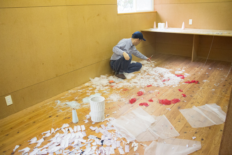 【写真】施設に床に破いた紙をばらまき、作品を作っている利用者。