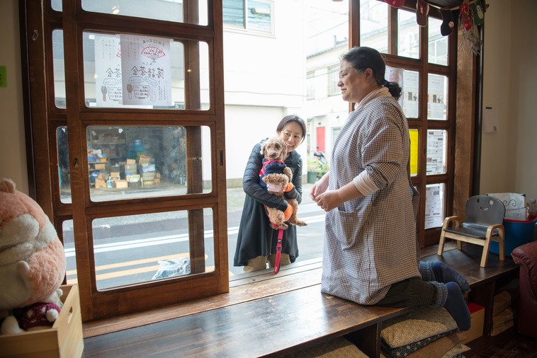 【写真】犬の散歩中の女性が縁側から、芝の家の中の人に話しかけている