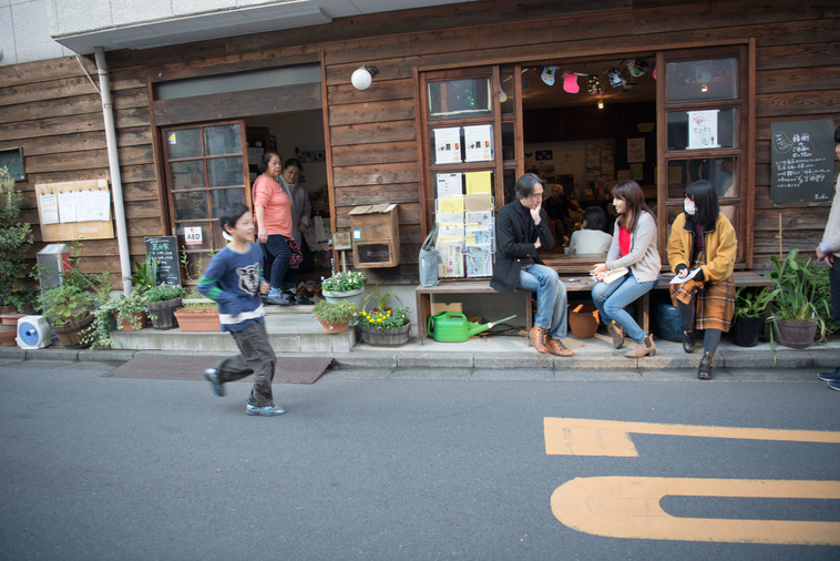 【写真】縁側に座ってインタビューをしている。近くでは子どもたちが走り回って遊んでいる