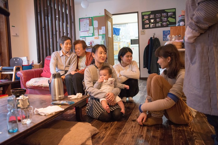 【写真】ソファに座って話をするおばあちゃん。近くには赤ちゃんを抱っこするお母さんと話をするかとうりょうこさんが