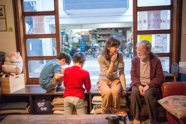 【写真】縁側に座っておばあちゃんと話をするかとうりょうこさん。その横では子どもたちがゲームをしていて、近くにいるけれど別々のことをしている、ということが自然に成り立っているのが感じられる