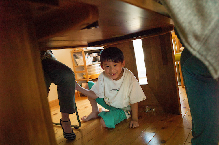 【写真】リビングのテーブルの下に隠れて、遊んでいる小学生。とても楽しそうだ。