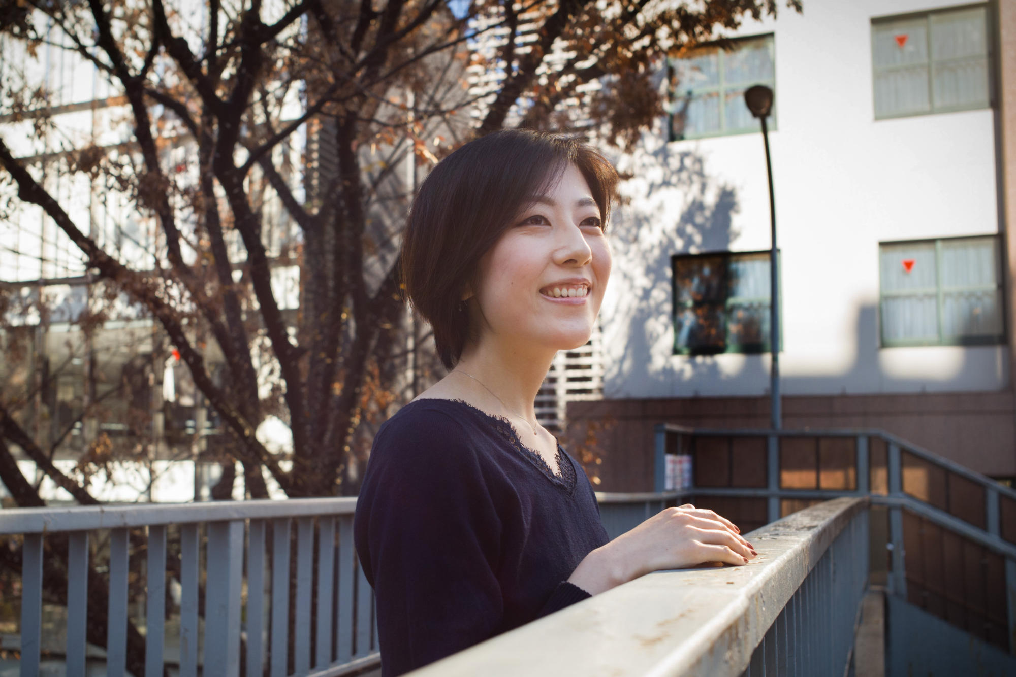 【写真】歩道橋の上で笑顔でほほえむつのみさん