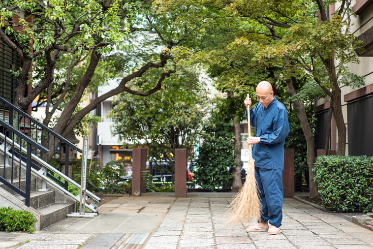 【写真】光明寺の入り口を竹ぼうきで掃いているまつもとしょうけいさん