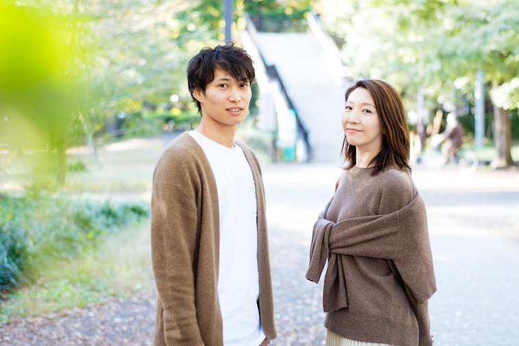 【写真】緑あふれる公園の前で並んでこちらを見つめるせんださんとせなさん