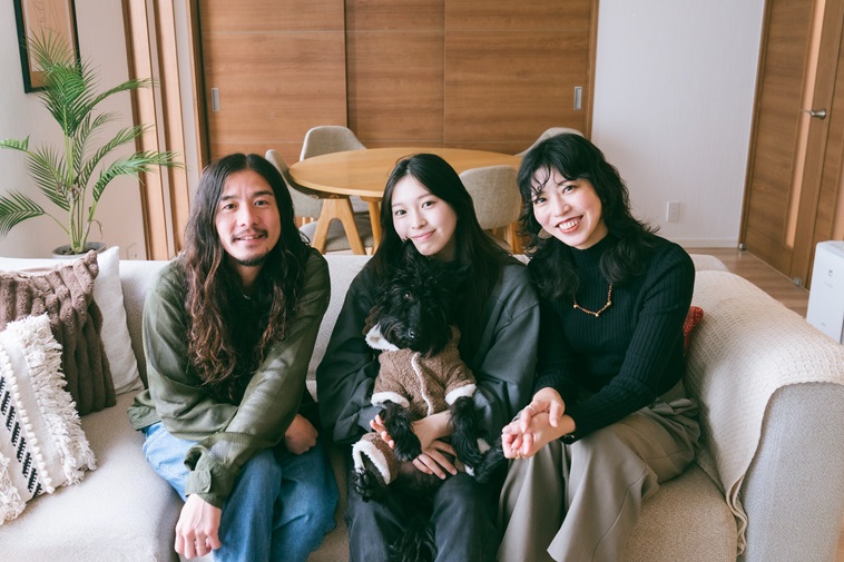 【写真】ソファーに座りカメラを見つめて微笑むいいたかゆうたさん、さえこさん、れいらさん