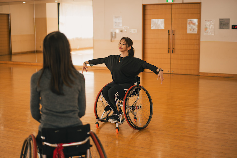 【写真】コーチに見てもらいながパラダンスのポーズをとるうめつさん