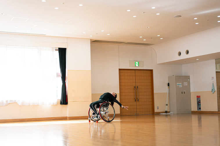 【写真】車いすに乗って後ろに反るようなポーズをしているうめつさん