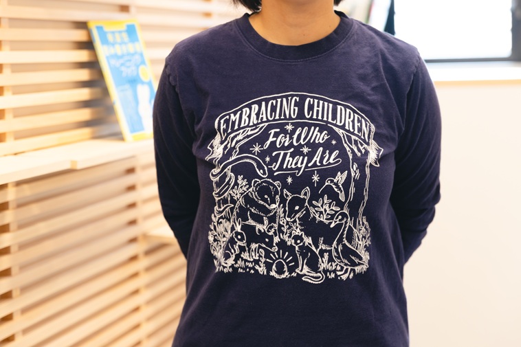【写真】スタッフが着用しているTシャツ。ネイビーの生地に白字で文字や絵が描かれている