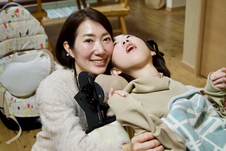 【写真】バギーに乗ったマコさんに頬を寄せこちらを見ているさくらさん