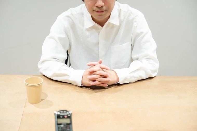 【写真】テーブルの上で両手を組むひろさん