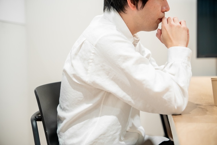 【写真】肘をテーブルについて手を口元に置くひろさんの横顔