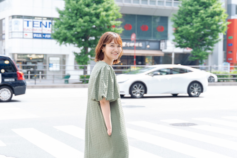 【写真】横断歩道の手前でカメラを見つめて微笑むむろいのぞみさん