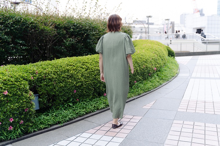 【写真】植え込みのそばを歩くむろいさんの後ろ姿