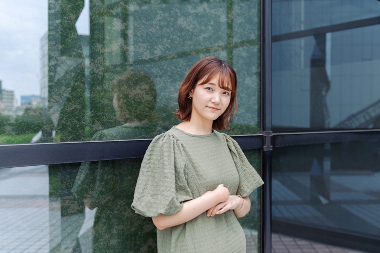 【写真】ビルを背もたれにカメラを見つめるむろいさん