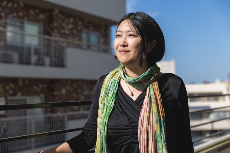 【写真】柵に手をかけ空を見つめながら微笑むふじきかずこさん